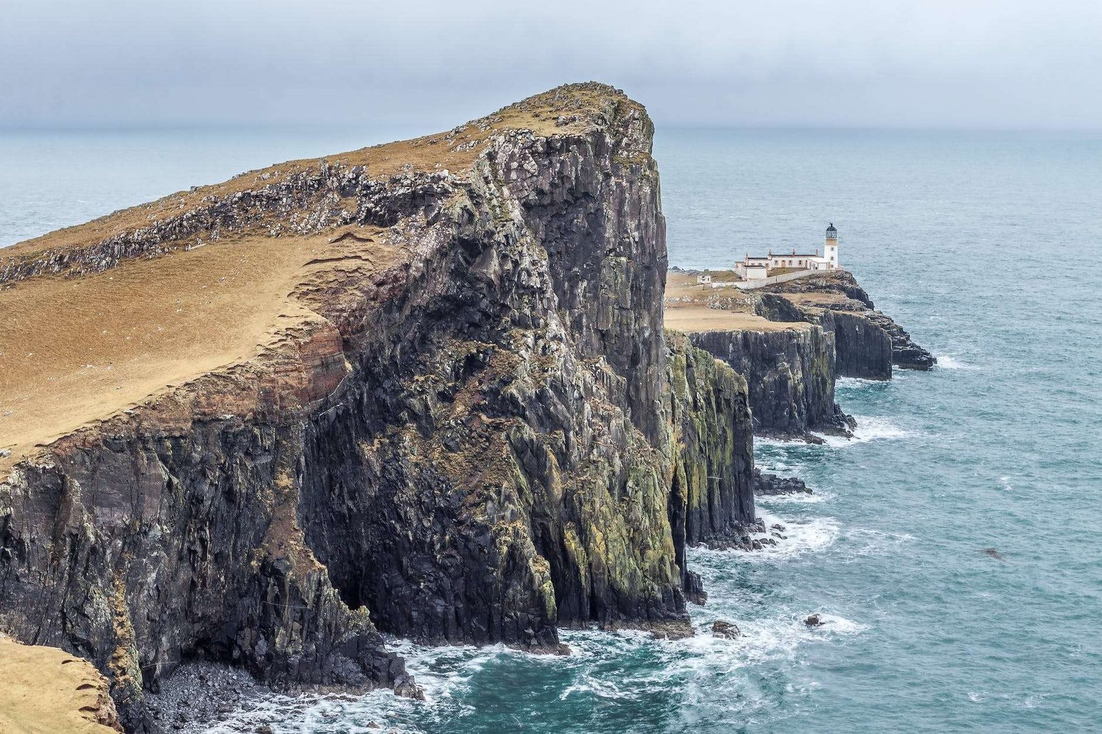 lighthouse on near body of water between rock formation